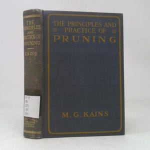 May include: A vintage book titled "The Principles and Practice of Pruning" by M.G. Kains. The book has a dark blue cover with gold lettering and a worn spine. The book is standing upright.