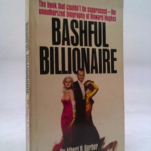 May include: A vintage paperback book titled "Bashful Billionaire" by Albert B. Gerber. The cover features a photo of three people and the text "The book that couldn't be suppressed - the unauthorized biography of Howard Hughes."