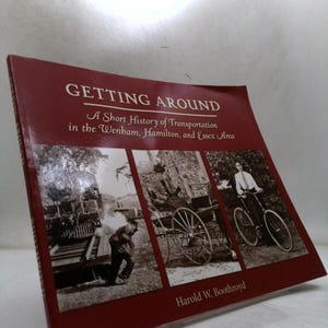 May include: A maroon book titled "GETTING AROUND" with the subtitle "A Short History of Transportation in the Wenham, Hamilton, and Essex Area." The cover features black and white images of a train, a horse-drawn carriage, and a bicycle.