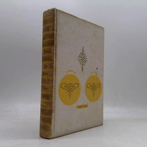 May include: A hardcover book with a white cover featuring two yellow circles containing dark brown decorative flourishes and a small yellow rectangle with the text "TEXTFELD". The spine has horizontal yellow stripes and dark brown text.