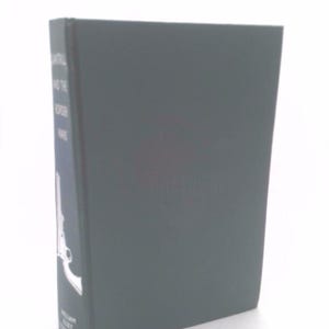 May include: A dark green hardcover book with the title "Lateral" and the subtitle "The Hacker Wars" printed on the spine. The book has a silver illustration of a gun on the front cover.