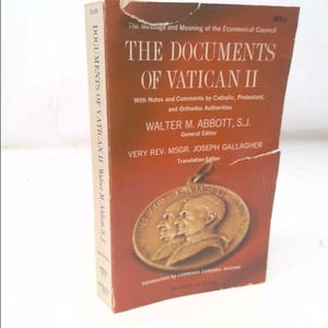 May include: A vintage book titled "THE DOCUMENTS OF VATICAN II" with a red cover and gold lettering. The book includes notes and comments by various religious authorities. A gold medallion with two faces is featured on the cover.