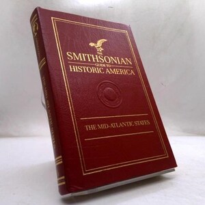 May include: A hardcover book titled The Smithsonian Guide to Historic America: The Mid-Atlantic States. The cover is deep red with gold embossed lettering and an eagle emblem. The spine and front cover feature gold border lines and a circular seal.