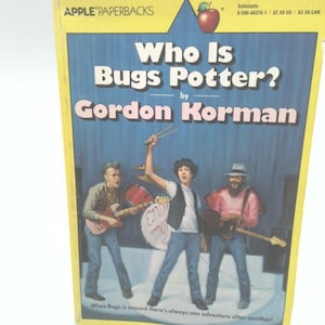 May include: A paperback book titled "Who Is Bugs Potter?" by Gordon Korman. The cover features a band playing instruments on a stage. The book is part of the Apple Paperbacks series.