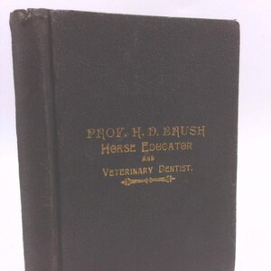 May include: A black book with gold lettering on the cover. The title reads "PROF. H. D. BRUSH HORSE EDUCATOR and VETERINARY DENTIST."