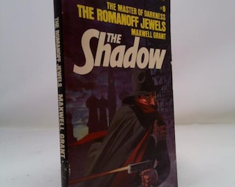 May include: Vintage paperback book titled "The Romanoff Jewels" by Maxwell Grant. The cover features a shadowy figure holding a gun, with the title "The Shadow" in large white letters. The book is a #9 in the series.