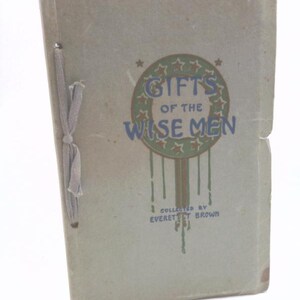 May include: Vintage book titled "Gifts of the Wise Men" with a light green cover. The title is in blue and brown, surrounded by a star-shaped design. The book is bound with a light gray ribbon.