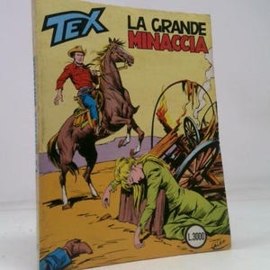 May include: A vintage comic book cover featuring a cowboy on horseback, a distressed woman, and a burning wagon. The title "TEX LA GRANDE MINACCIA" is displayed in bold letters. The artwork is in a classic comic book style.