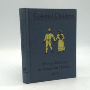 May include: A hardcover book titled "Colonial Children" with a dark blue cover. The cover features a gold illustration of two figures in colonial attire holding hands. The text "Source Readers in American History" and "No. 1" are also visible.