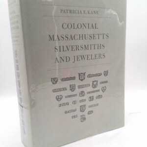 May include: A gray book with the title "Colonial Massachusetts Silversmiths and Jewelers" by Patricia E. Kane. The cover features a collection of silversmith hallmarks.