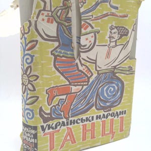 May include: A vintage book cover with a yellow background and a colorful illustration of a person dancing. The text on the cover reads "Українські народні танці" which translates to "Ukrainian Folk Dances".