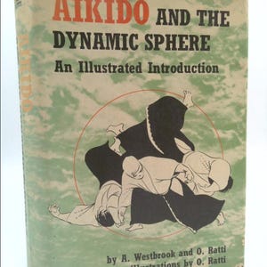 May include: Book cover with a green background and a black and white illustration of two people practicing Aikido. The title of the book is "Aikido and the Dynamic Sphere: An Illustrated Introduction" by A. Westbrook and O. Ratti.
