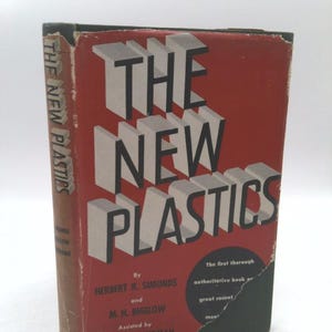 May include: A red book with the title "The New Plastics" in bold black letters. The book is by Herbert R. Simonds and M. H. Bigelow, assisted by Joseph V. Sherman. The text on the cover states that it is the first thorough authoritative book on the subject of plastics.