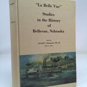 May include: A beige book cover with the title "La Belle Vue" Studies in the History of Bellevue, Nebraska. The book cover features a black and white illustration of a steamboat on a river.