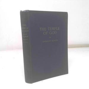 May include: A hardcover book titled "The Temple of God" by Annalee Skarin. The book has a dark blue cover with the title and author's name in a lighter color. The book is standing upright.