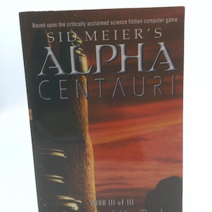 May include: A paperback book titled Sid Meier's Alpha Centauri: Twilight of the Mind, Book III of III by Michael Ely. The cover features a dark, sunset-toned landscape with a tall, textured structure and bold white text against a dark background.