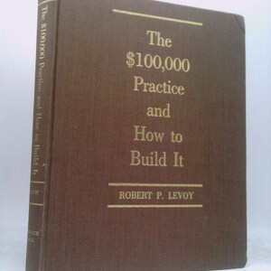 May include: A brown hardcover book titled "The $100,000 Practice and How to Build It" by Robert P. Levoy. The title and author's name are in gold lettering. The book's spine also has text.