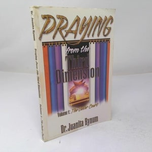 May include: A softcover book titled Praying from the Third Dimension, Volume 1: The Outer Court by Dr. Juanita Bynum. The cover features gold lettering, a central graphic of a glowing altar, and vertical stripes in orange, purple, and white.
