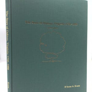 May include: A green hardcover book titled "The Story of Oakton, Virginia: 1758-1990" with a gold tree illustration and the author's name, D'Anne A. Evans, printed in gold.