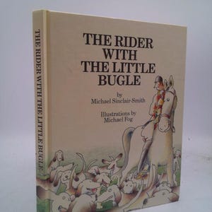 May include: A hardcover book titled "The Rider With The Little Bugle" by Michael Sinclair-Smith, with illustrations by Michael Fog. The cover features a drawing of a rider on a horse, surrounded by dogs.