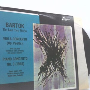 May include: A vinyl record album featuring Bartok's "The Last Two Works." The album cover has a blue and white section with text and a black and purple abstract art design. The album is titled "Viola Concerto" and "Piano Concerto No. 3 (1945)."