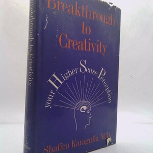 May include: A hardcover book titled "Breakthrough to Creativity" with a dark blue cover. The title and author's name are in orange. The cover features a white illustration of a head with radiating lines and the text "your Higher Sense Perception".