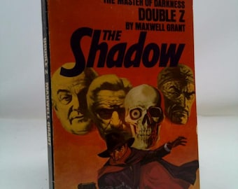 May include: Vintage paperback book titled "The Shadow" by Maxwell Grant. The cover features a pulp illustration of a figure in a hat and cape holding a gun, with the title in large black letters. The background is orange.