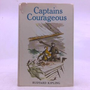 May include: A vintage hardcover book titled "Captains Courageous" by Rudyard Kipling. The cover features an illustration of two figures on a ship's deck, with a mast and sail in the background. The title is in blue lettering.