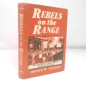 May include: A hardcover book titled "Rebels on the Range" by Arthur W. Thurner. The book has an orange cover with white text. The cover features a black and white image of a crowd of people. The book's spine also displays the title.