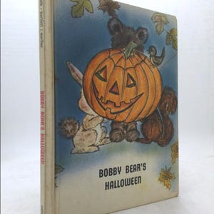 May include: A vintage children's book cover featuring a cartoon bear wearing a jack-o'-lantern on its head. The book is titled "Bobby Bear's Halloween".