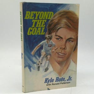 May include: A vintage book titled "Beyond The Goal" with a blue and yellow cover. The cover features a portrait of a young man and a soccer player in action. The author's name, Kyle Rote, Jr., is also visible.