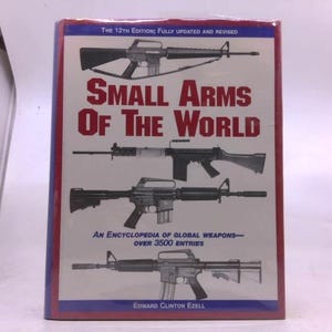 May include: A book titled "Small Arms of the World" with images of various firearms. The cover features the text "The 12th Edition; Fully Updated and Revised" and "An Encyclopedia of Global Weapons - Over 3500 Entries".
