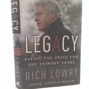 May include: A hardcover book titled "LEGACY" featuring a portrait of a man on the cover. The book's title is in large white letters with the "A" in red. The author's name, Rich Lowry, is prominently displayed.