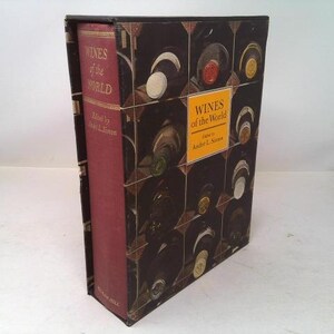 May include: A hardcover book titled "Wines of the World" in a decorative case. The book's spine is burgundy, and the case features a dark brown design with wine bottles. The title is displayed on the spine and the case.
