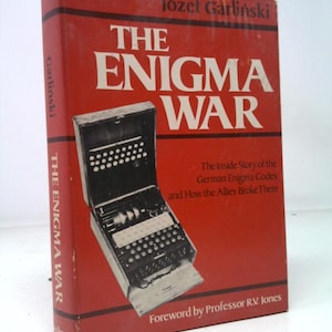 May include: A vintage book titled "The Enigma War" by Józef Garliński. The cover is red with white text and features an illustration of an Enigma machine. The book details the story of German Enigma codes and how the Allies broke them.