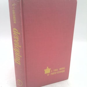 May include: A vintage book titled "Developing" by C.I. Jacobson. The book has a dusty rose cover with gold lettering and a small illustration. The book is part of "A Focal Manual of Photo-Technique".