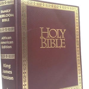 May include: A burgundy leather-bound Holy Bible with gold lettering and accents. The cover reads "Holy Bible" in large, ornate letters. The spine includes "Family Heirloom Bible," "African American Edition," and "King James Version."