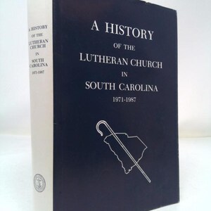 May include: A blue book with the title "A History of the Lutheran Church in South Carolina 1971-1987". The book cover features a white outline of the state of South Carolina with a shepherd's crook.