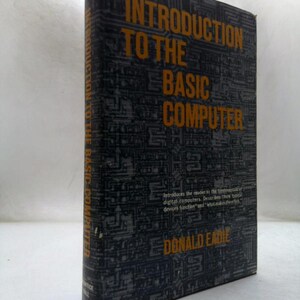 May include: A hardcover book titled Introduction to the Basic Computer by Donald Eadie. The cover is dark gray with a black circuit board pattern and bold orange text. The spine also features the title and author in orange against a dark background.