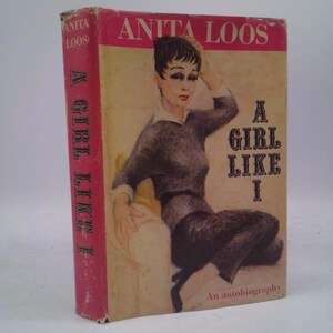 May include: Vintage hardcover book titled "A Girl Like I" by Anita Loos. The cover features an illustration of a woman in a dark sweater and pants. The spine is red with the title and author's name. An autobiography.