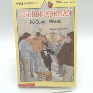 May include: A paperback book titled "No Coins, Please" by Gordon Korman. The cover features a crowd of people and the text "Funny money???". The book is part of the Apple Paperbacks series and published by Scholastic.