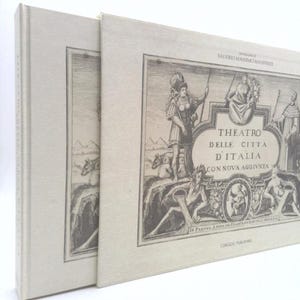 May include: Two cream-colored books with a black and white illustration on the front cover. The illustration depicts a woman in a helmet and armor riding a horse. The text on the cover reads "THEATRO DELLE CITTA D'ITALIA CON NOVA AGGIVNTA".