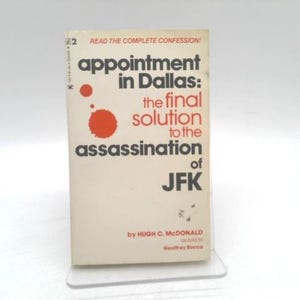 May include: A vintage paperback book titled "Appointment in Dallas: the final solution to the assassination of JFK." The cover is off-white with black and red text and graphics. The author is Hugh C. McDonald.