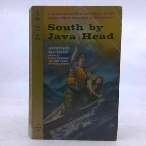 May include: Vintage paperback book titled "South by Java Head" by Alistair MacLean. The cover features an illustration of a man and woman in a boat, with the man reaching up. The book has a yellow and brown cover.