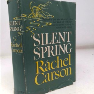 May include: A hardcover book titled "Silent Spring" by Rachel Carson. The book has a dark green cover with the title and author's name in white and yellow. The cover also features an illustration of water and plants.