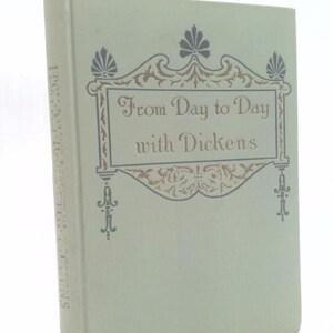 May include: A vintage book titled "From Day to Day with Dickens" in a light green cover. The title is in elegant script within a decorative frame, with floral accents. The spine reads "From Day to Day with Dickens".