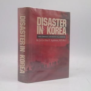 May include: A hardcover book titled "Disaster in Korea" with a red and maroon cover. The title is in large, white, block letters. The book's spine also displays the title vertically. The author's name is visible.