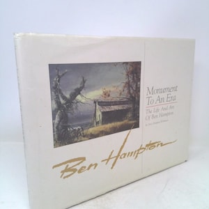 May include: A white book cover with a painting of a barn and a tree in the background. The title of the book is "Monument To An Era: The Life and Art of Ben Hampton". The book cover also features the artist's signature, "Ben Hampton".