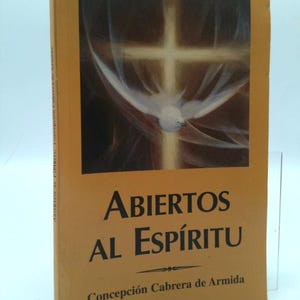 May include: A book titled "Abiertos al Espíritu" by Concepción Cabrera de Armida. The cover features a cross with a dove and a soft, golden-yellow background. The book's title is in large, black letters.