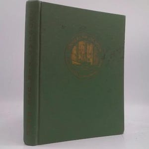 May include: A hardcover book with a green cover and gold lettering on the spine. The front cover features a gold circular emblem with a landscape scene. The book is standing upright.